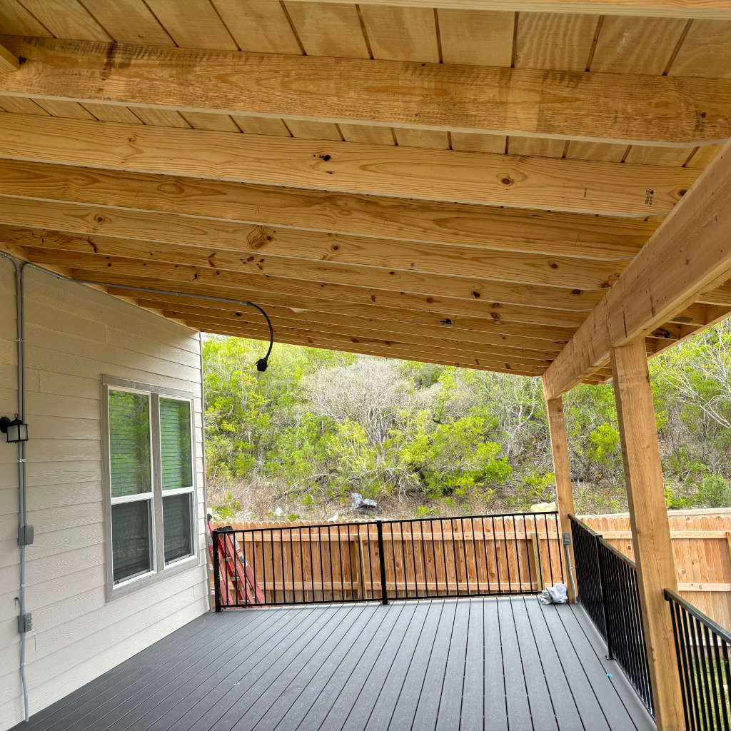 Elegant covered porch built by Alamo City Decks and Patios featuring natural wood columns and decking with scenic backyard views.